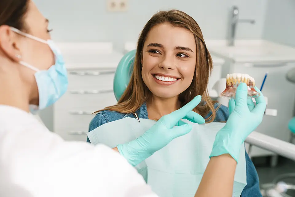 A Smile That Lasts a Lifetime: The Importance of Replacing Lost Teeth 1 dentist woman showing teeth imitation to her smiling
